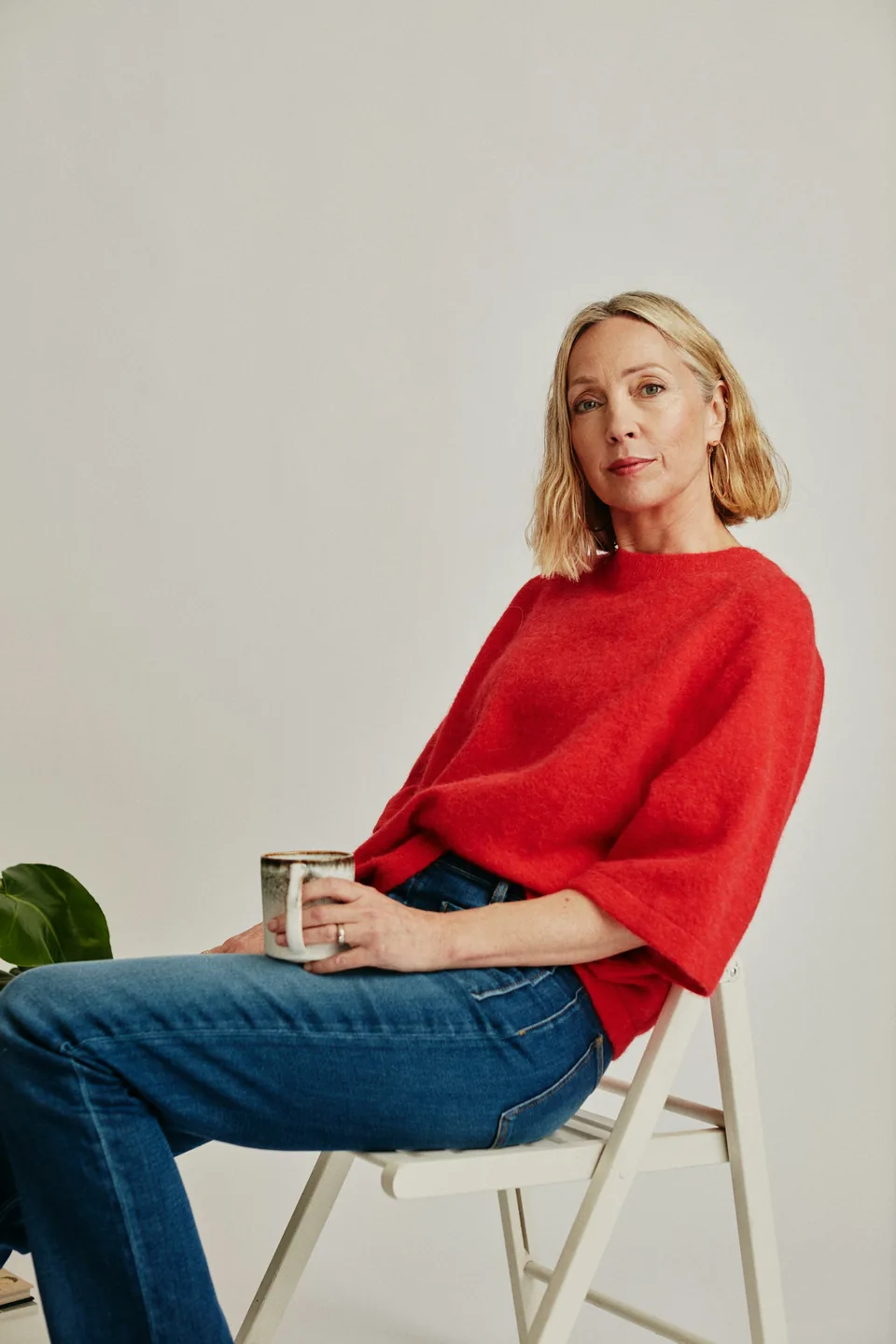a woman sitting on a chair holding a cup of coffee