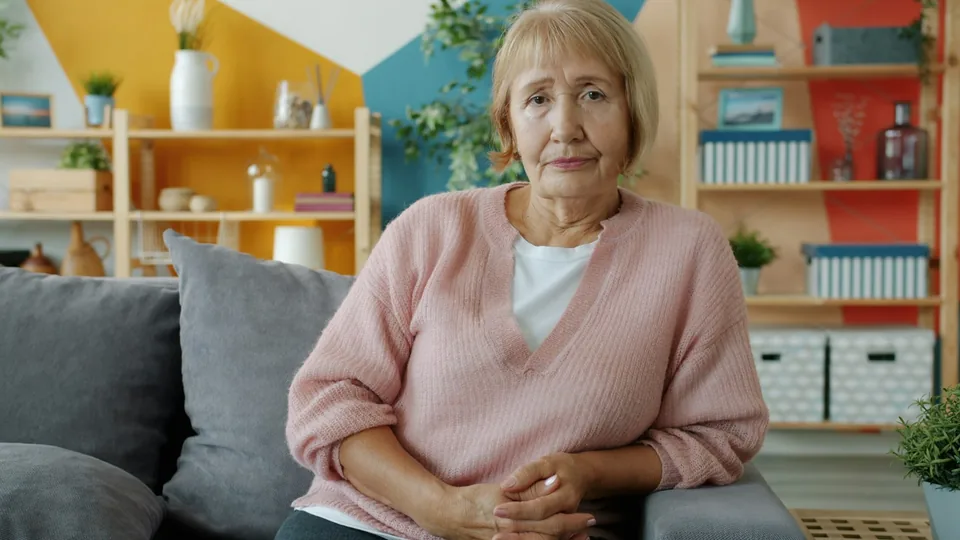 Elderly woman sitting on a couch in a living room