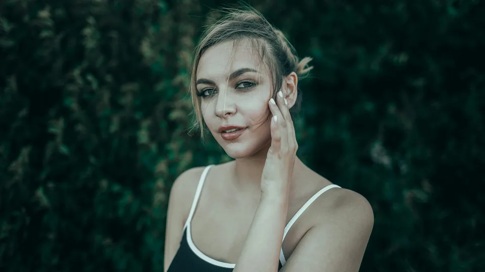 Young woman with hand on cheek looking at camera