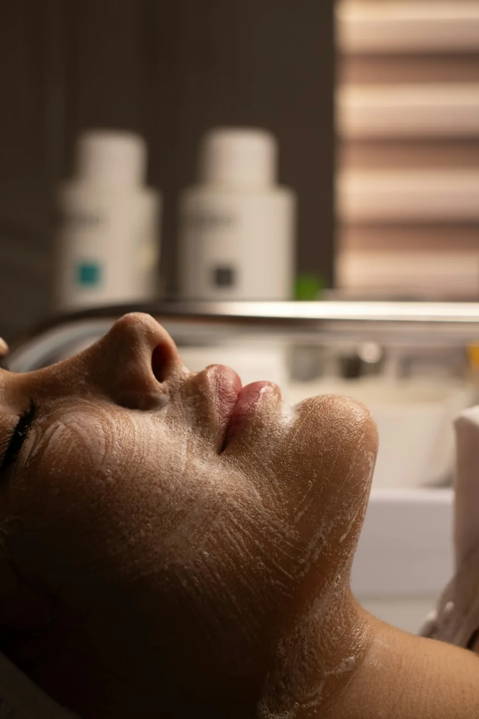 Woman's face with cleansing foam during facial treatment